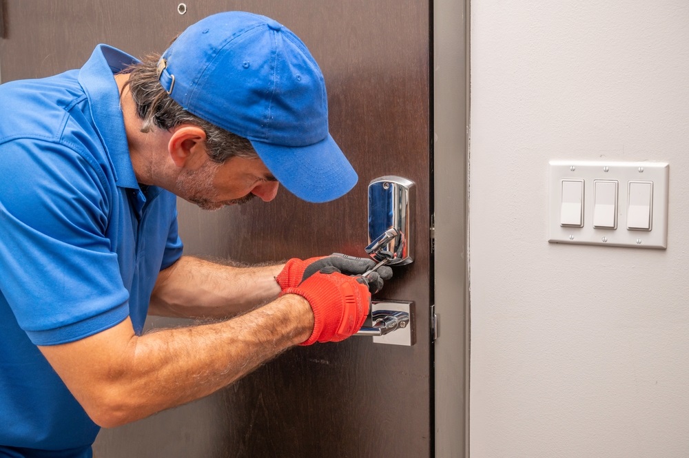 A residential locksmith using a screwdriver on a deadbolt lock