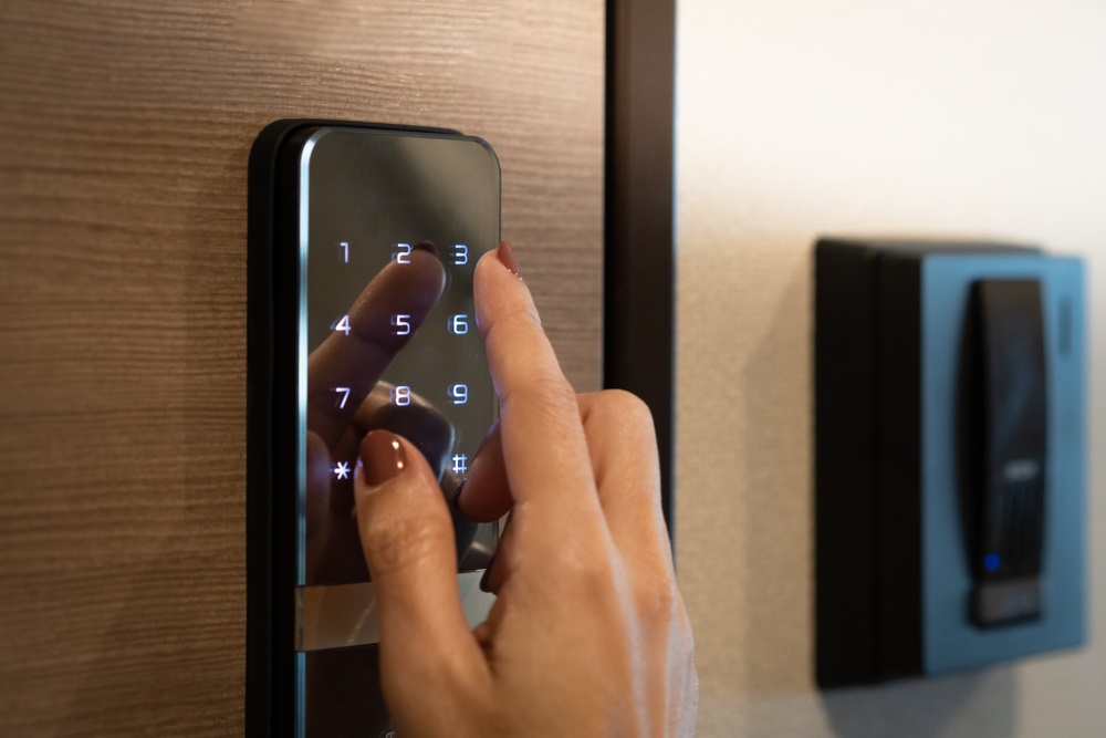 Closeup of a woman's finger entering password code on the smart digital touch screen keypad entry door lock in front of the room. Self Check-in, Airbnb, Modern security, Keyless, Temporary codes